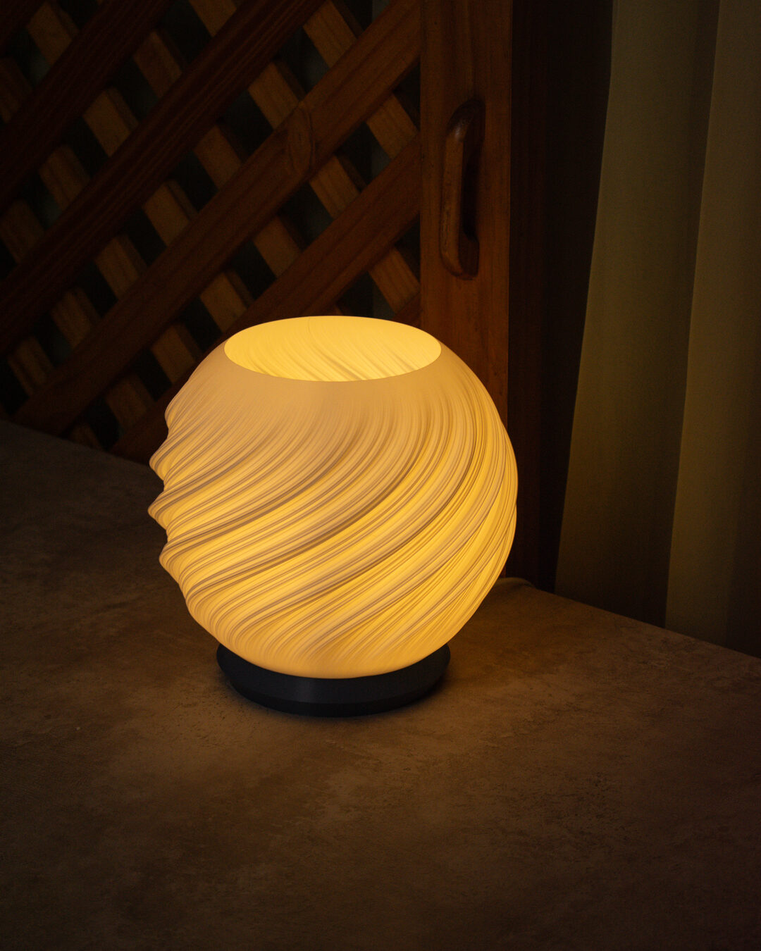 Luminária Aura acesa, luz quente atravessando a cúpula esférica em espiral