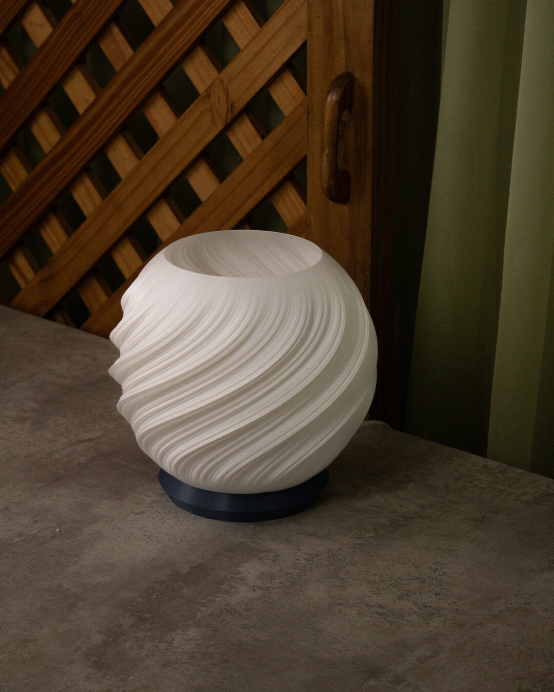 Luminária Aura apagada, cúpula branca em espiral sobre mesa de concreto